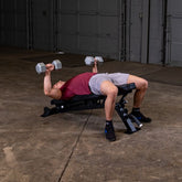 Man exercising on a Flat Incline Bench with dumbbells in a gym setting.
